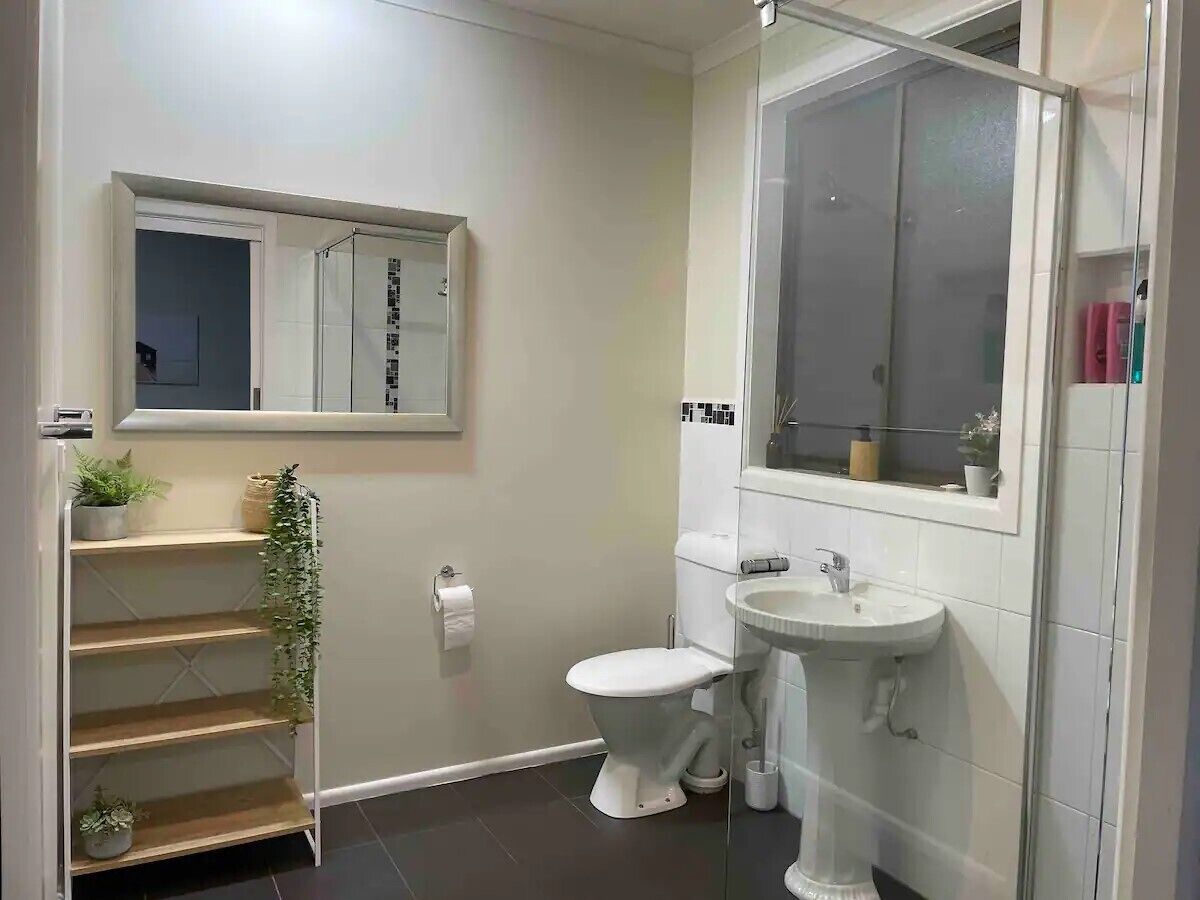 Une salle de bain avec des toilettes, un lavabo et une petite fenêtre située au-dessus des toilettes.