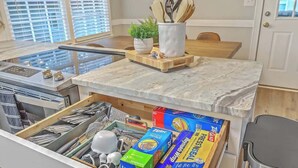 A kitchen with a marble countertop, a drawer with utensils, and a box of Ziploc bags. - Family Fun near CHAS Summerville and Nexton (Summerville)