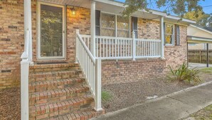 A two-story house with a brick exterior, a front porch with white railings, and a welcome sign on the door. - Family Fun near CHAS Summerville and Nexton (Summerville)