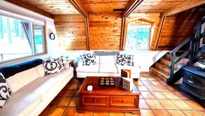 L’intérieur d’un chalet en bois, avec un canapé, une table basse et un escalier.