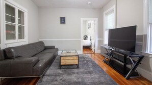 Un salon moderne avec un canapé en cuir, une table basse en verre et un téléviseur à écran plat posé sur un meuble noir.