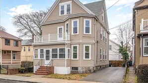Une maison à deux étages avec un balcon au deuxième étage, un porche à l’avant et des fondations en pierre.