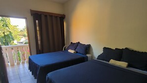 A hotel room with two beds, a balcony, and a view of greenery outside. - Hotel y Restaurante Casa Jardines (San Benito)