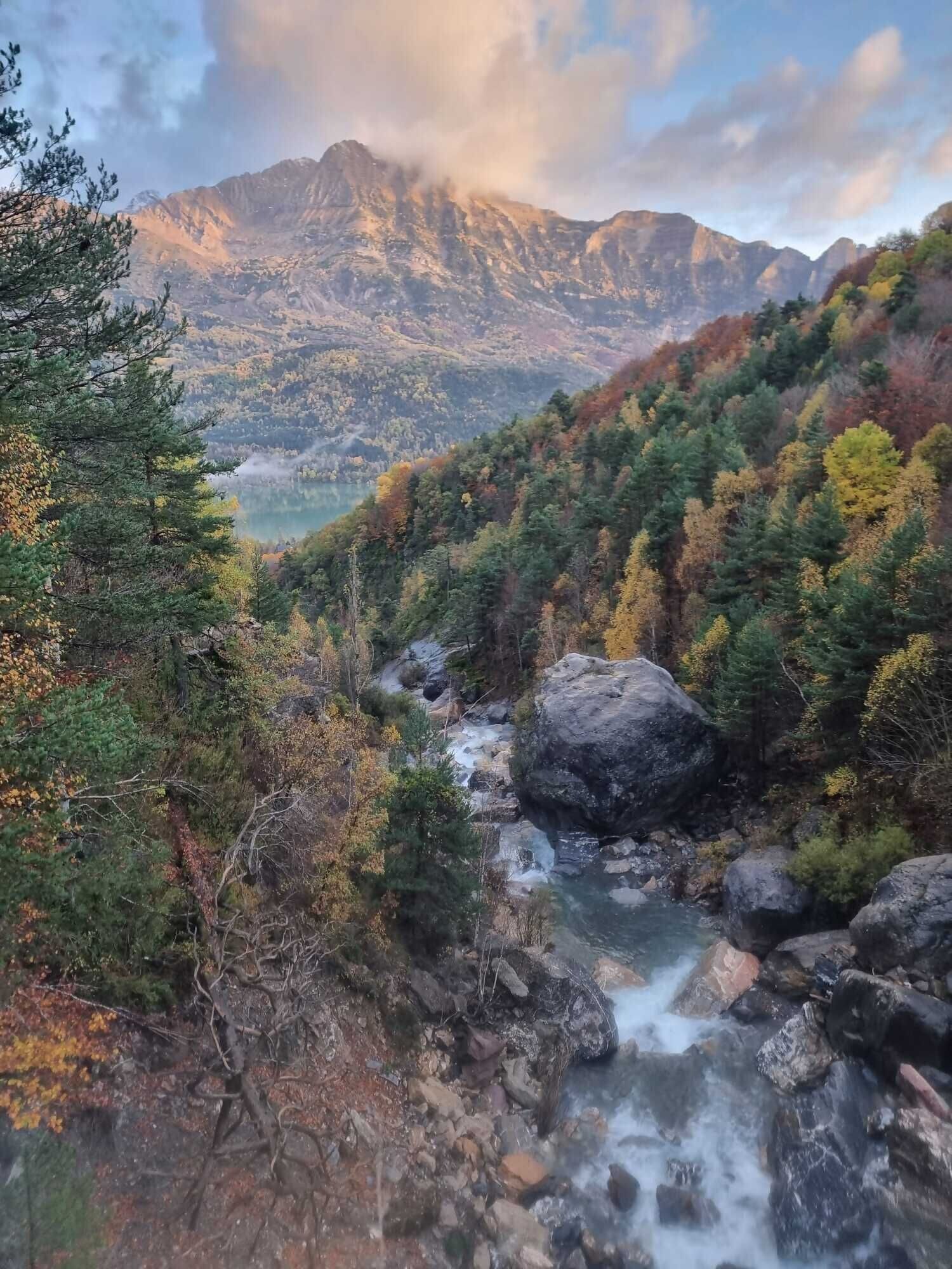 Un paisaje montañoso con un río serpenteante, un bosque denso y una vista despejada del valle.