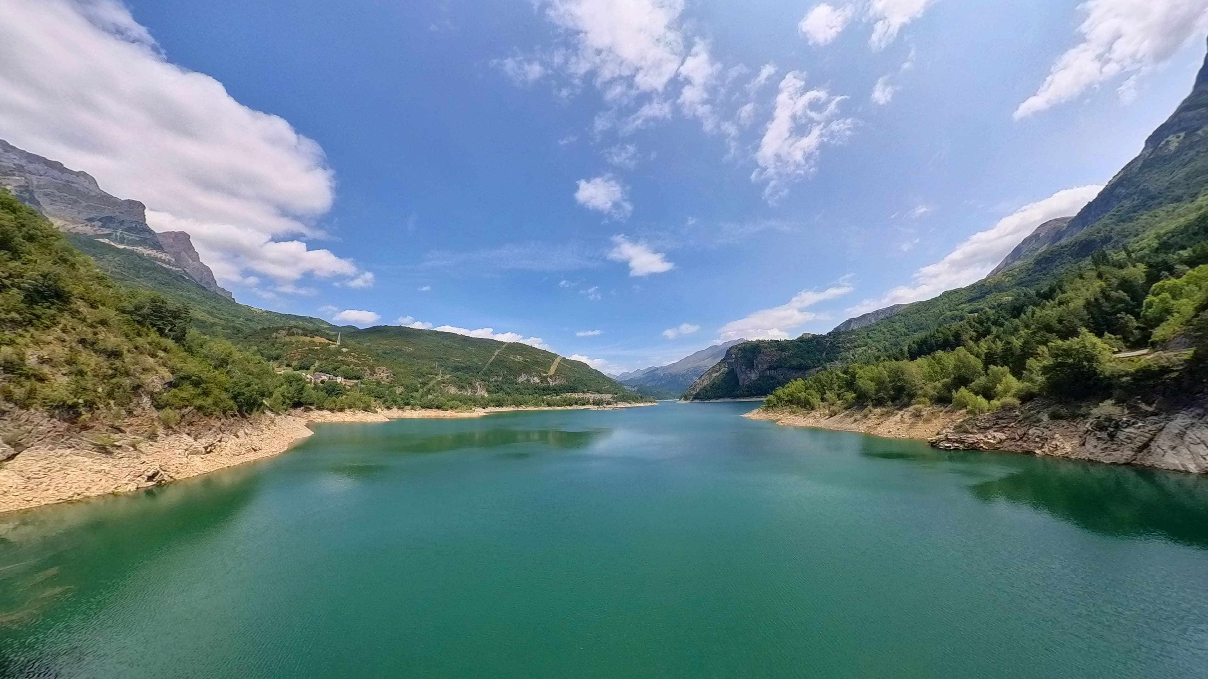 A calm lake surrounded by mountains with a clear sky.