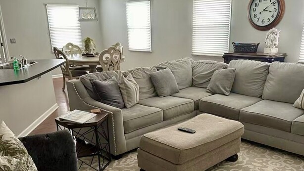 A living room with a sectional sofa, ottoman, and a dining area with a table and chairs. - Close to UK, Keeneland and downtown. Rare Country living in the city.  (Lexington)