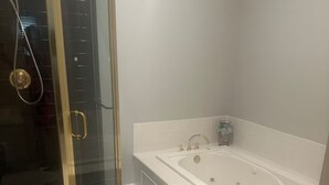 A bathroom with a glass-enclosed shower, a white bathtub, and a patterned rug. - Close to UK, Keeneland and downtown. Rare Country living in the city.  (Lexington)