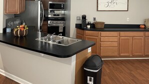 A modern kitchen with wooden cabinets, a black countertop, stainless steel appliances, and a wall-mounted sign. - Close to UK, Keeneland and downtown. Rare Country living in the city.  (Lexington)