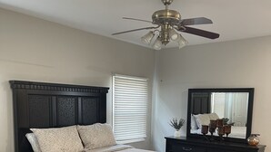 A bedroom with a dark wood bed, a ceiling fan, a large mirror, and a window with blinds. - Close to UK, Keeneland and downtown. Rare Country living in the city.  (Lexington)