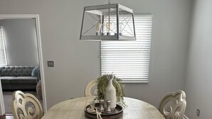 A dining area with a round table, four chairs, a hanging light fixture, and a window with blinds. - Close to UK, Keeneland and downtown. Rare Country living in the city.  (Lexington)