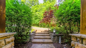 A stone staircase leading to a covered entrance, surrounded by lush greenery and stone walls.