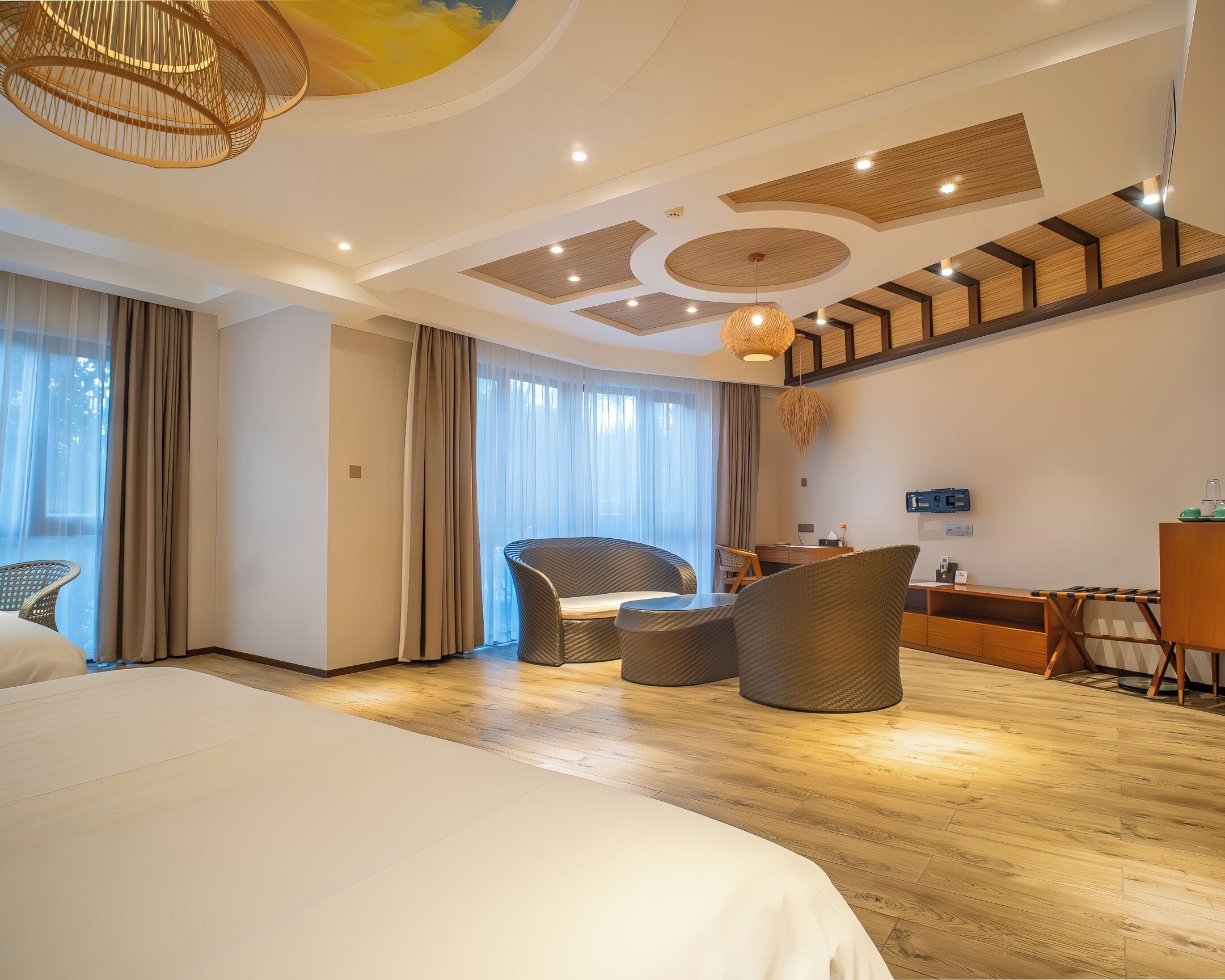 A hotel room with a large bed, a seating area with chairs, a desk, and a television.