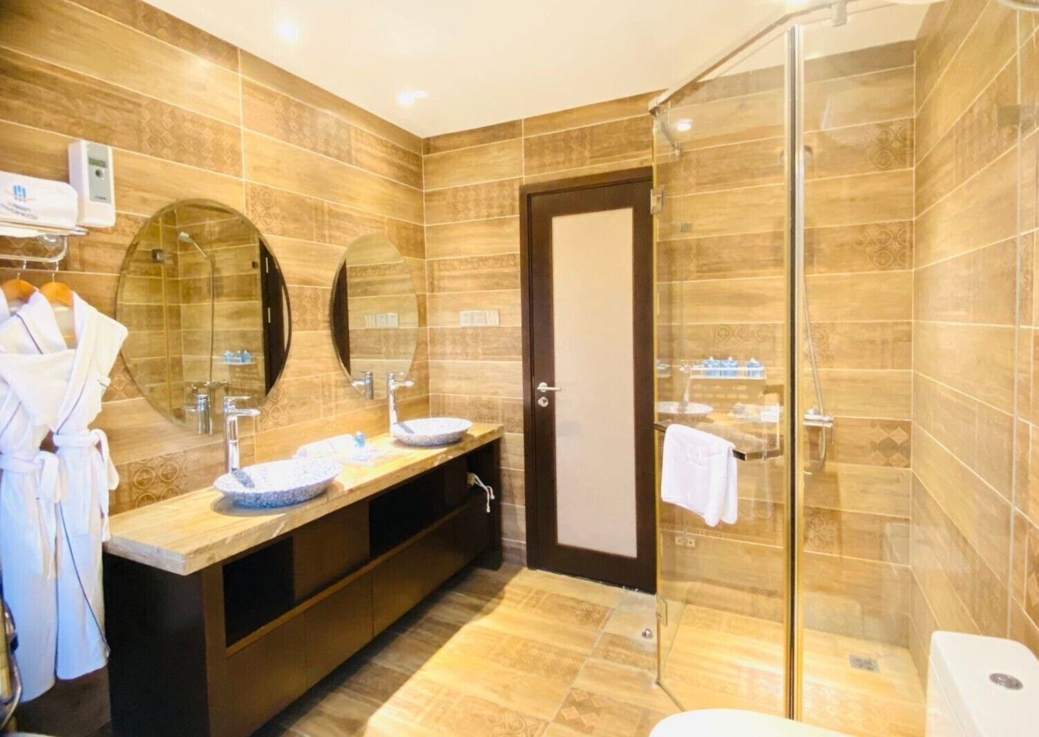 A modern bathroom with a double sink vanity, a glass shower enclosure, and a large mirror.
