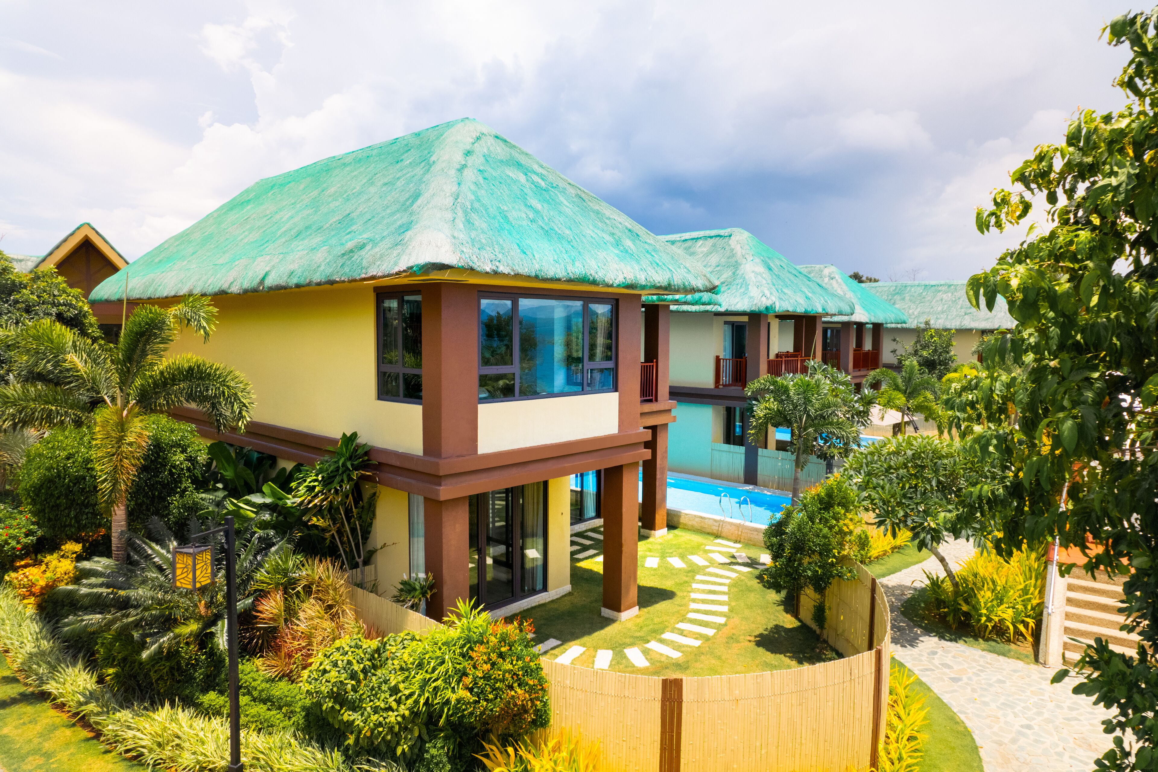 A resort with modern buildings, a swimming pool, and lush greenery.