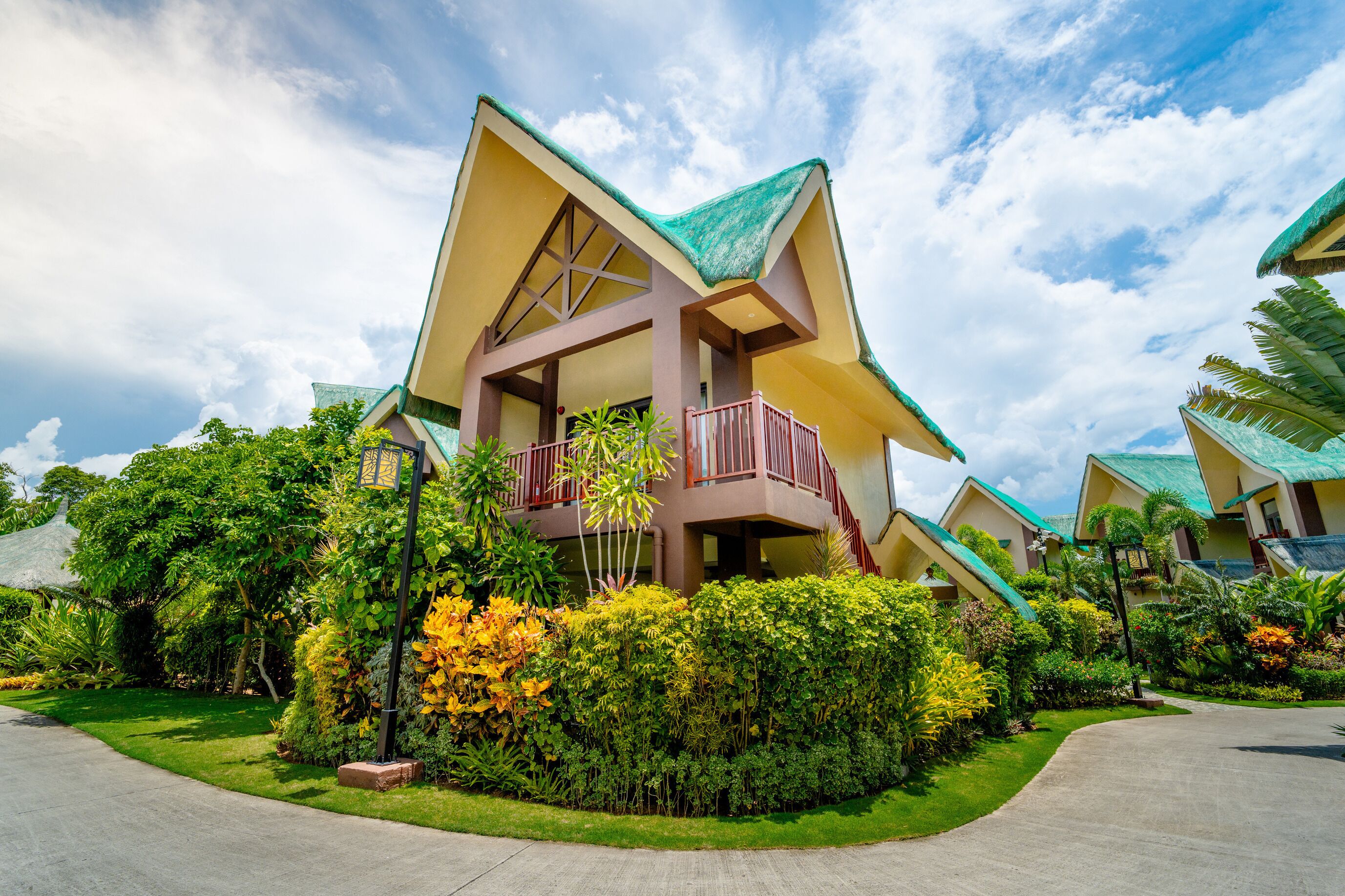 A multi-story hotel with a unique architectural design, featuring balconies and a lush garden.