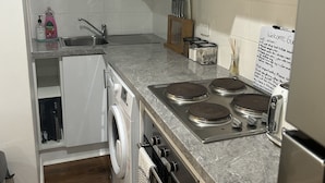A compact kitchen with white cabinets, a built-in oven, a microwave, and a sink. - Pet friendly private studio, walking distance to lake  (Halekulani)