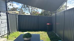 A patio area with a table and a bench, surrounded by a metal fence. - Pet friendly private studio, walking distance to lake  (Halekulani)