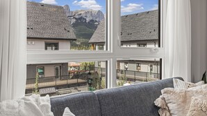 Una sala de estar con un ventanal que da a una montaña y un balcón.