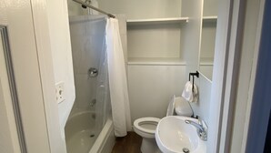 Baño con ducha, inodoro, lavamanos y espejo con luces.
