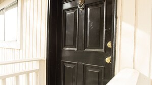 A black door with a doormat that reads "WELCOME".
