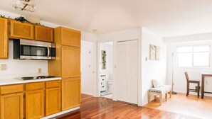 A modern kitchen with wooden cabinets, a built-in microwave, and a dining area with a table and chairs.