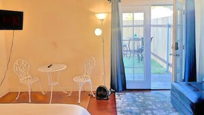 A room with a bed, two white chairs, a small table, a fan, and a sliding glass door leading to an outdoor area with a table and chairs. - MaGiQ Private Master En-Suite w Private Bathroom, No Shared Spaces (Spring Valley)