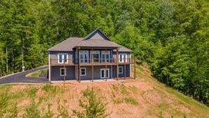 A two-story house with a balcony on the upper floor, surrounded by a forested hillside. - Butterfly Mountain Cabin for 8 w/amazing view+wifi, 3 bdrm, 3.5 bath, & firepit (Franklin)