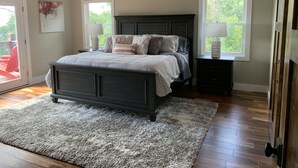 A bedroom with a dark wooden bed, a large window, and a ceiling fan. - Butterfly Mountain Cabin for 8 w/amazing view+wifi, 3 bdrm, 3.5 bath, & firepit (Franklin)