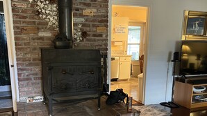 Una sala de estar con chimenea de ladrillo, un televisor y una alfombra.