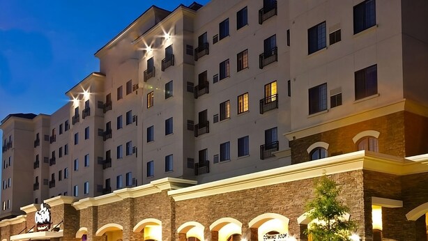 Een meerhoog hotel met verlichte balkons en een bordje met de tekst 'Binnenkort geopend'.