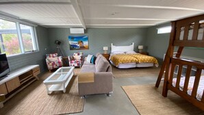 A bedroom with a bed, a sofa, a TV, and a crib. - This Pet Friendly property is the perfect escape to the beauty of Inverloch (Inverloch)