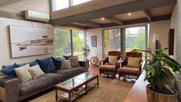 A spacious living room with a large window, a sofa, armchairs, a coffee table, and a potted plant. - This Pet Friendly property is the perfect escape to the beauty of Inverloch (Inverloch)