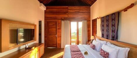 Un dormitorio amplio con una cama grande, techo de madera y un televisor sobre un mueble de madera.