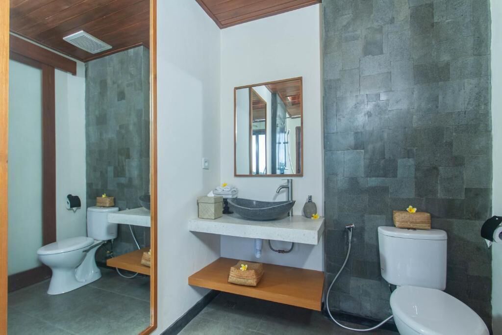 Een moderne badkamer met een wit toilet, een wastafel op een voetstuk en een grote spiegel.