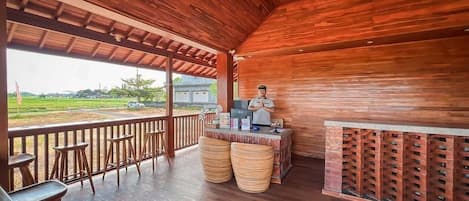 A wooden interior with a bar area, seating, and a view of the outdoors.