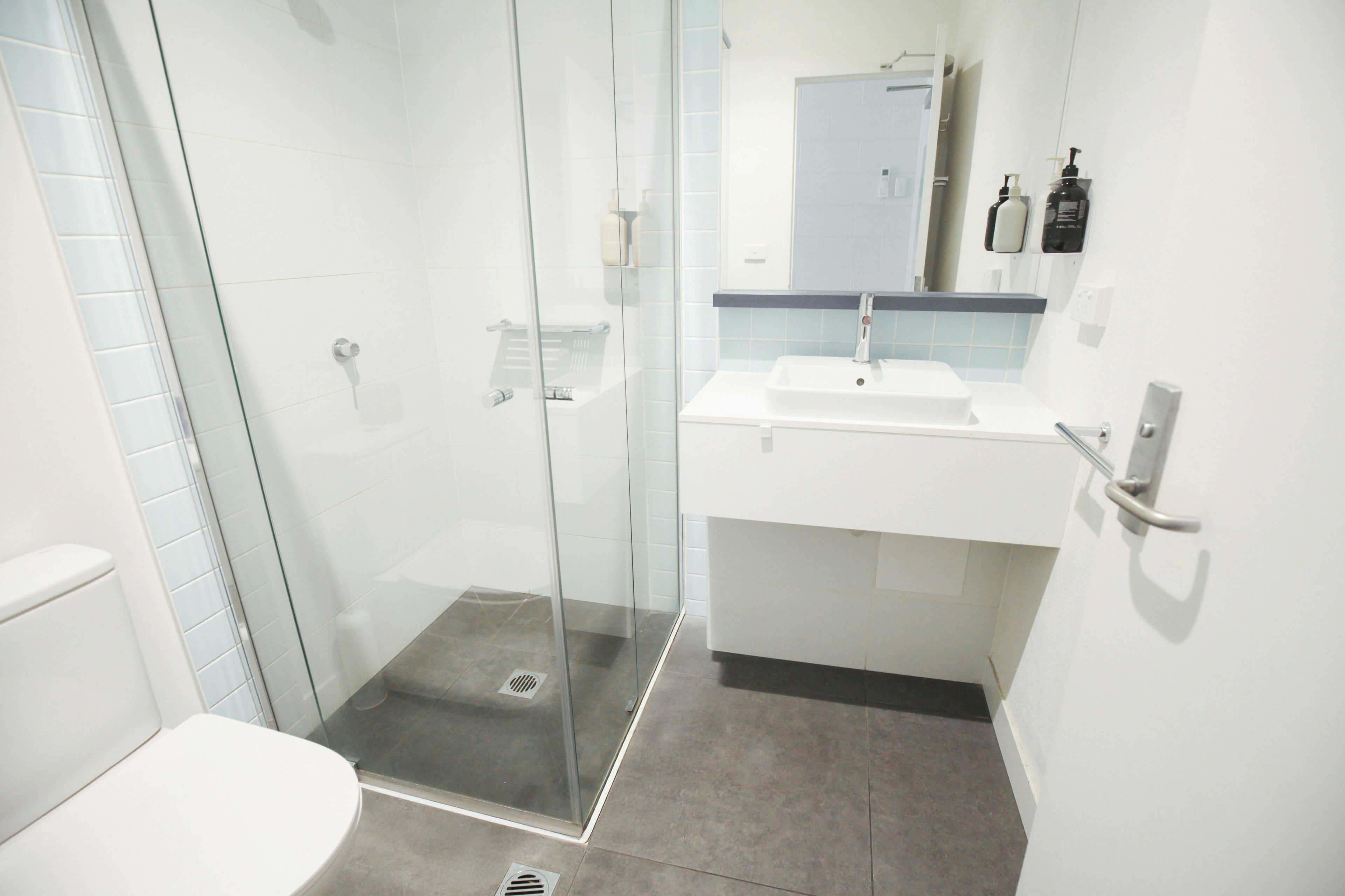 A modern bathroom with a glass-enclosed shower, a white sink, and a mirror above it.