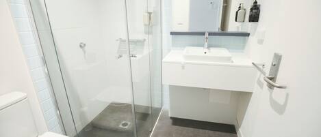 A modern bathroom with a glass-enclosed shower, a white sink, and a mirror above it.