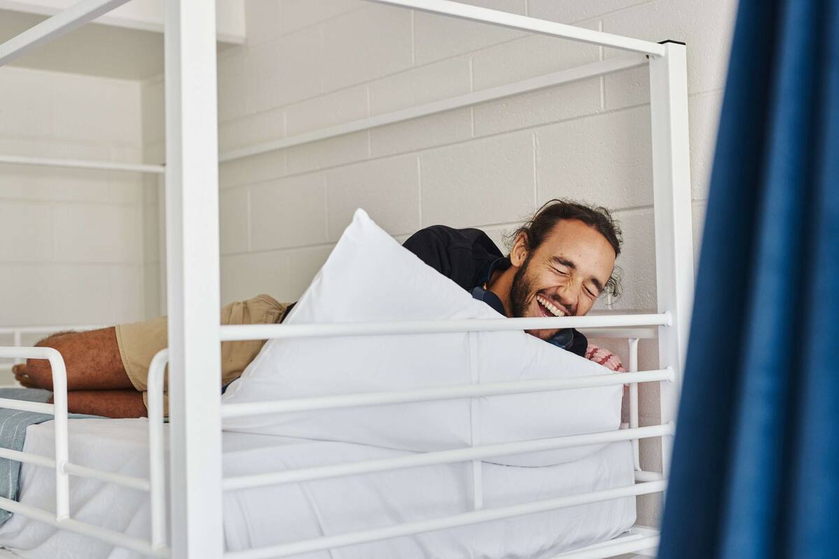 A bunk bed with white metal railings and white bedding.