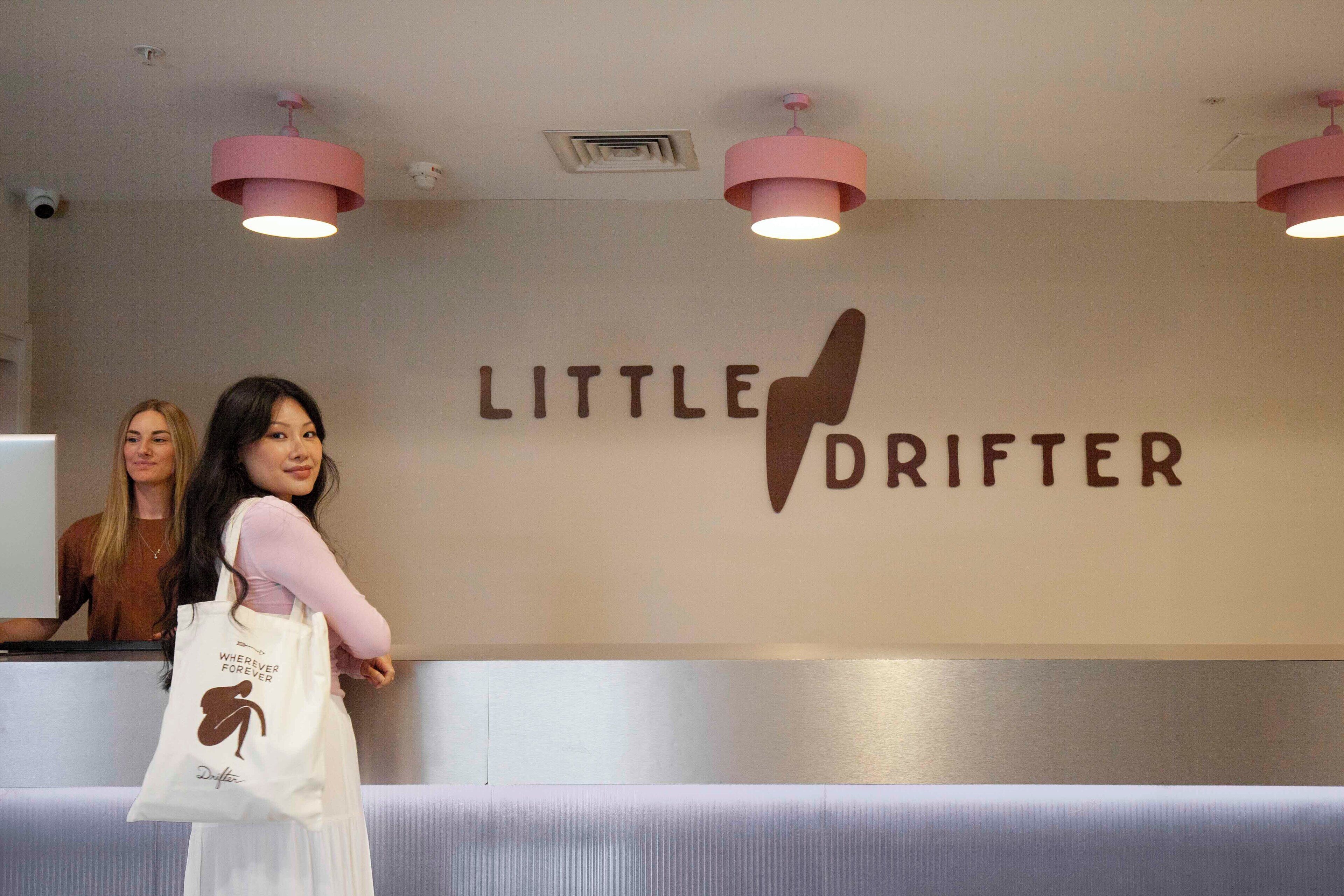 A reception area with a wall sign reading "LITTLE DRIFTER" and a white tote bag with a logo.