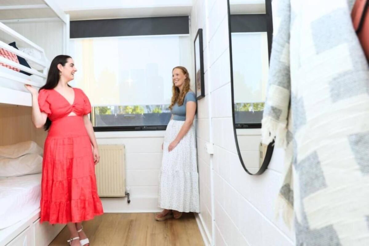 A room with a bed, a window, and a mirror on the wall.