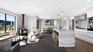 Una cocina moderna con una isla central, un comedor y un rincón acogedor con chimenea.