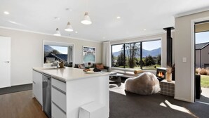 Una cocina moderna con una isla central, ventanas amplias con vistas a la montaña y una zona de estar acogedora con chimenea.