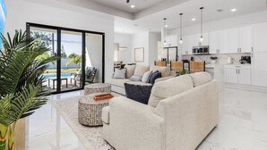 A modern living room with a sofa, coffee table, and a view of a pool. - Heated Saltwater I Pool Game Room | Firepit I BBQ (Cape Coral)