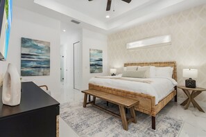 A bedroom with a large bed, bedside tables, a bench, and artwork on the walls. - Heated Saltwater I Pool Game Room | Firepit I BBQ (Cape Coral)