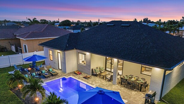 A residential property with a swimming pool, outdoor seating, and a patio area. - Heated Saltwater I Pool Game Room | Firepit I BBQ (Cape Coral)