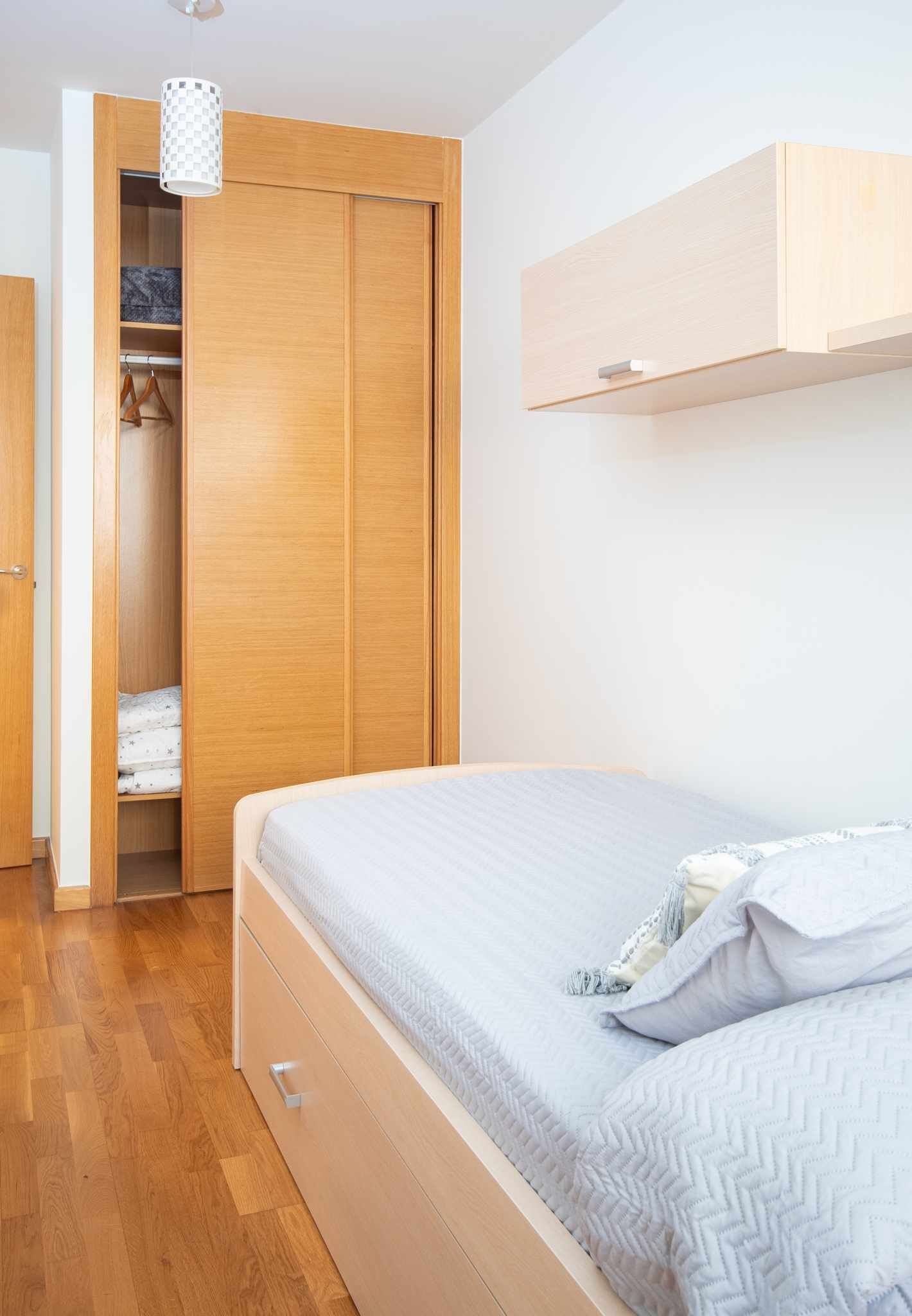 Une chambre à coucher avec un lit, une armoire en bois et un luminaire suspendu.
