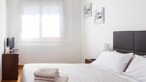 Une chambre à coucher avec un grand lit, une table de chevet, une lampe et des œuvres d’art accrochées au mur.