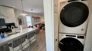 Une cuisine moderne dotée d’un îlot central, de tabourets de bar et d’un lave-linge et d’un sèche-linge à double porte.