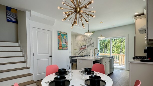 Un espace de salle à manger moderne avec une table ronde, des chaises roses et un lustre original.
