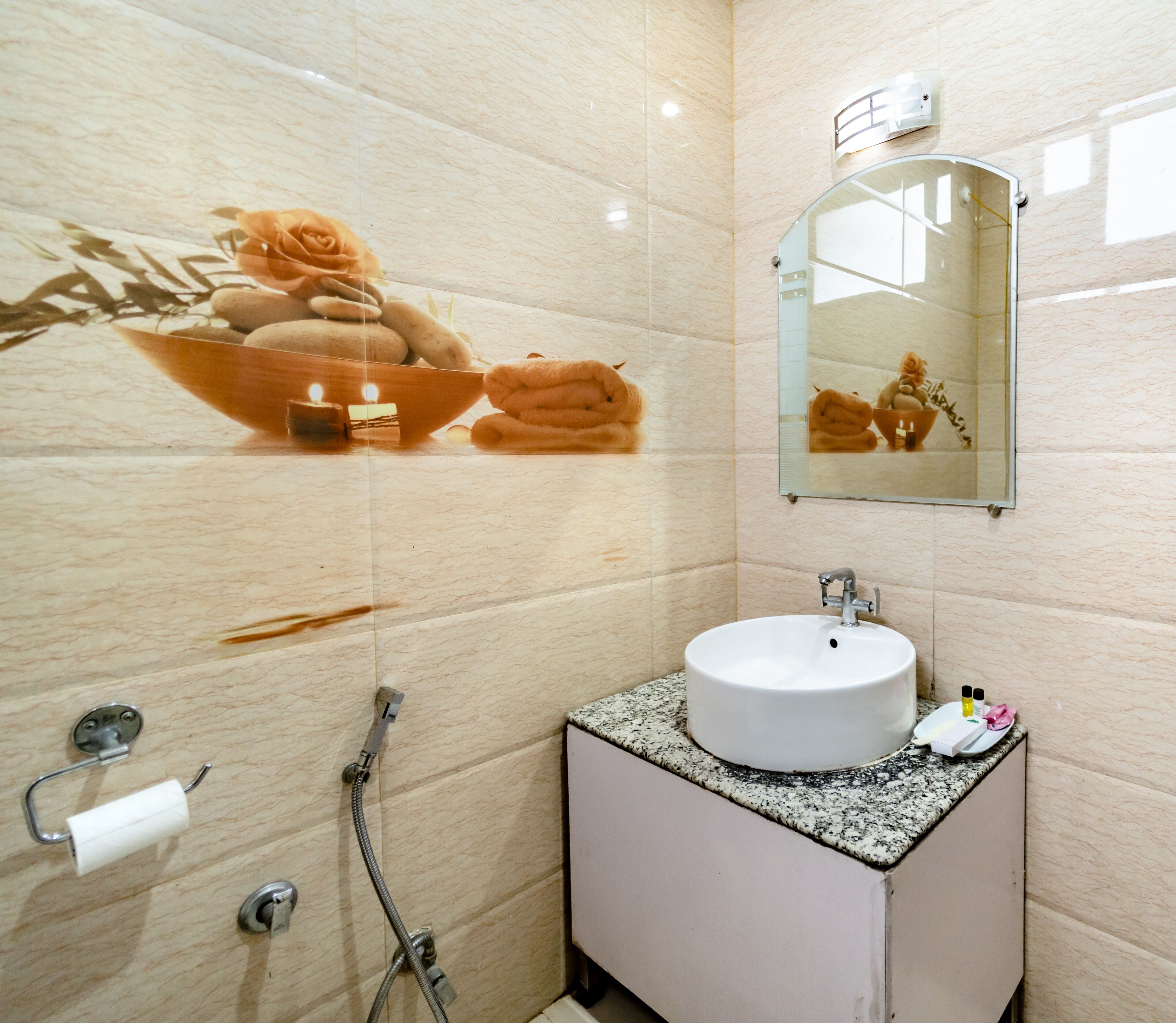 A bathroom with a marble wall, a sink with a mirror, a towel rack, and a shower.